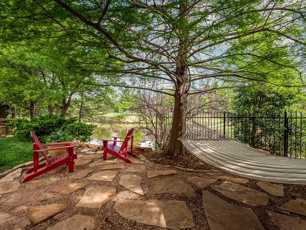 Shaded flagstone terrace with Adirondack chairs under a mature tree