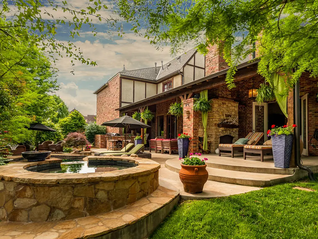 Raised stone patio with a spa, stone steps and landscaped lawn